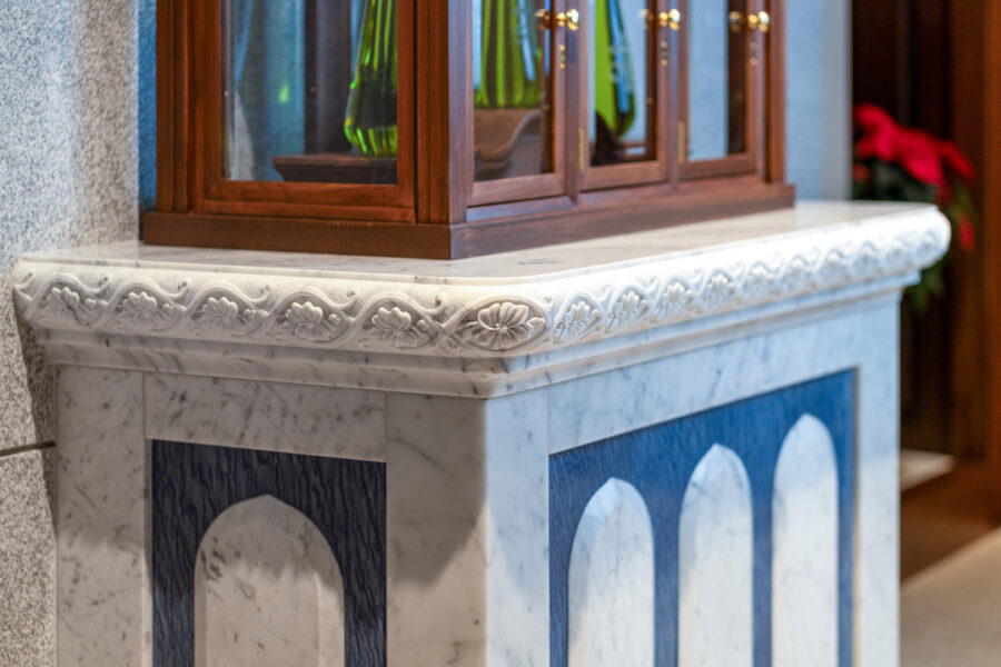 artisan hand-carving marble with chisel and hammer in workshop showing precision and artistry of sacred stonework